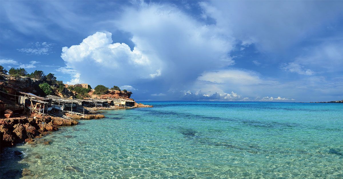 Crystal-clear waters in Ibiza with a rocky coastline, blue sky and Mediterranean horizon: a perfect image to inspire calm and summer.
