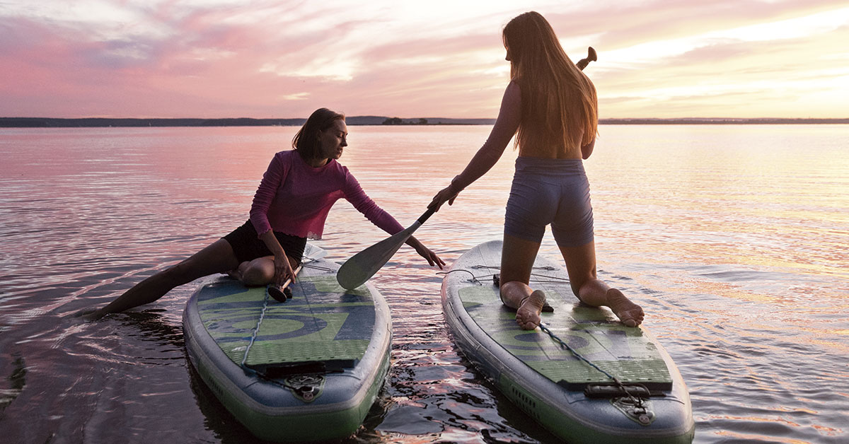 dos chicas haciendo paddle surf en la puesta de sol ibiza