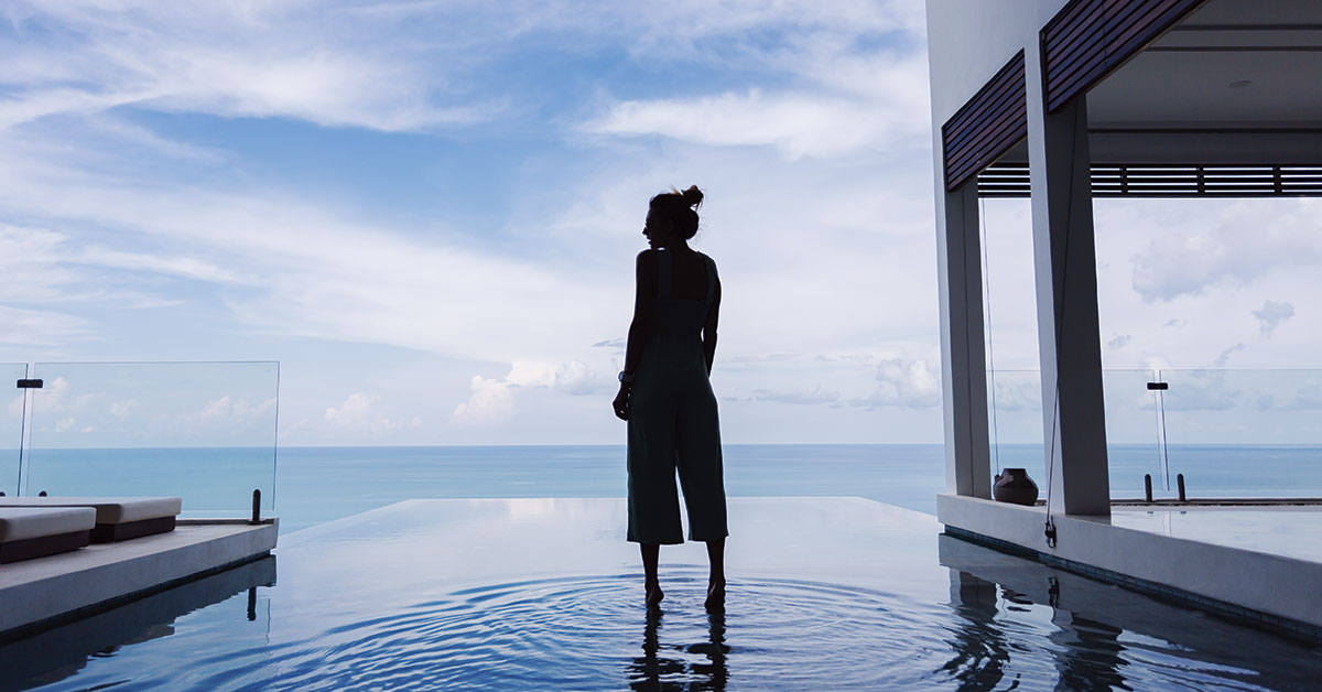 silueta mujer caminando sobre infinity pool con mar de fondo