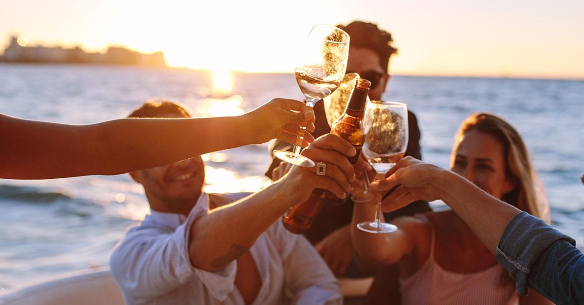 Group of friends toasting on a boat at sunset in Ibiza, with the sea and golden Mediterranean light in the background.