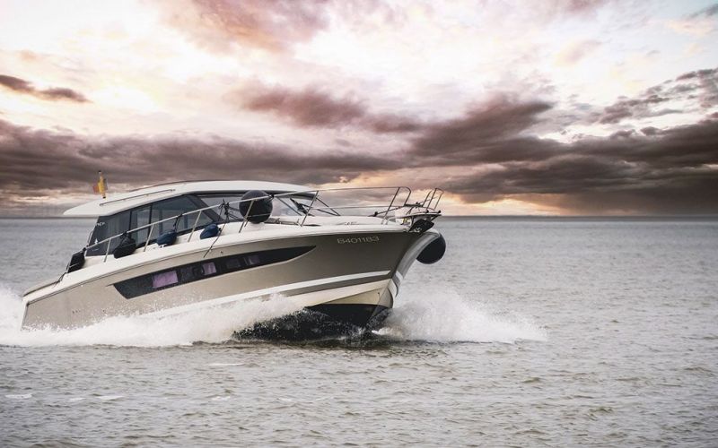 Lancha motora de lujo navegando por el mar Mediterráneo, con el cielo cubierto de nubes y la luz cálida del atardecer en el horizonte. La embarcación avanza entre las olas, transmitiendo potencia, elegancia y libertad para disfrutar de una experiencia náutica en Ibiza.